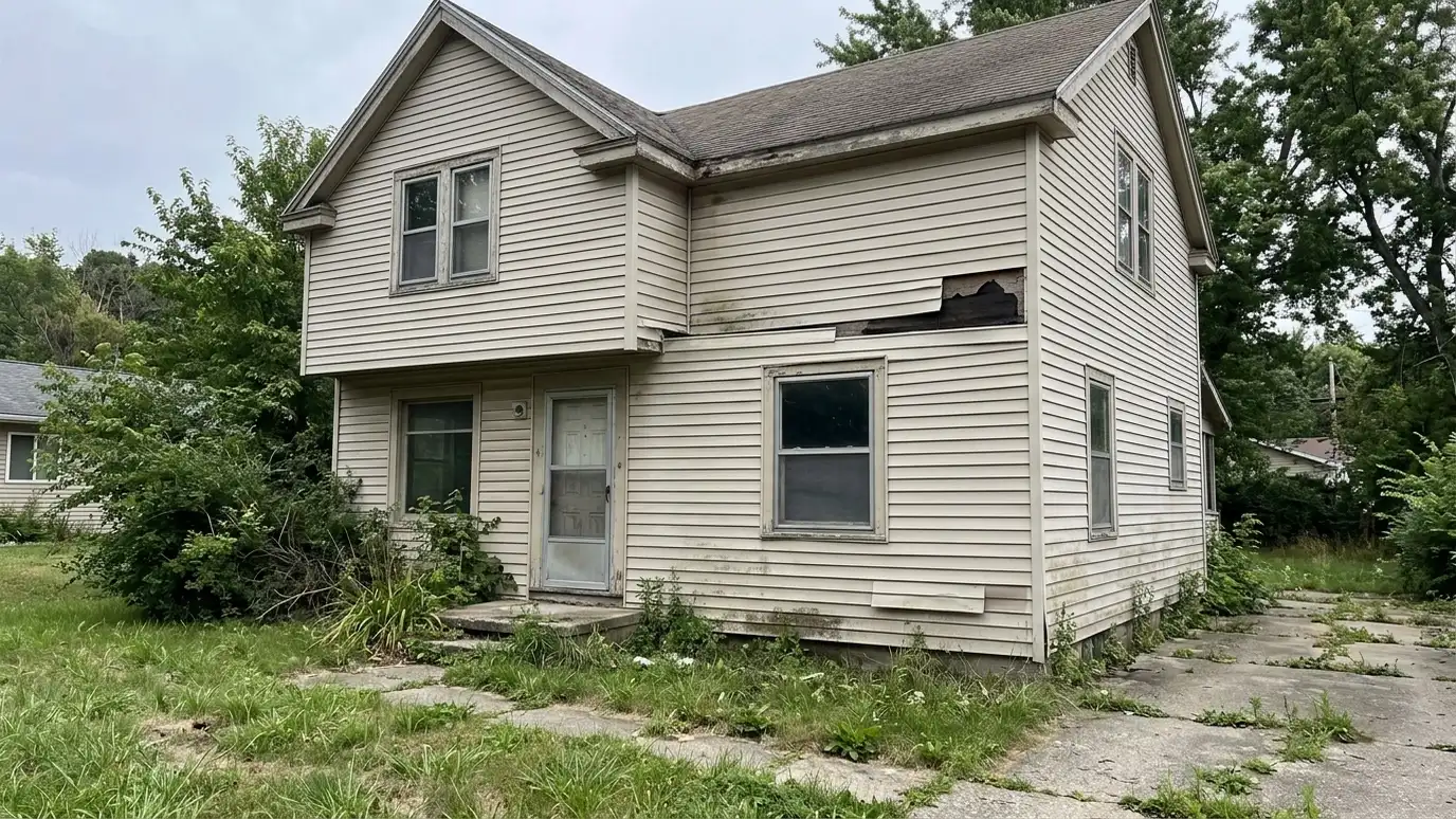 Before: a house exterior with a two-story house with faded, cracked and warped vinyl siding and dull trim